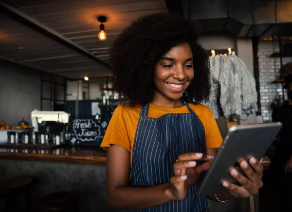 Sorridente donna di razza mista con afro navigazione su tablet digitale in caffetteria. — Foto Stock