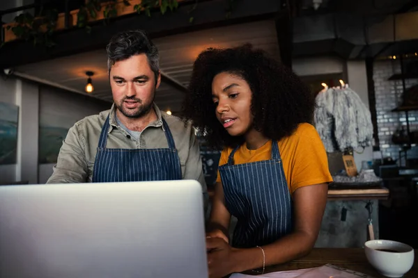 Cameriere e cameriera imparare nuovo menu fuori computer portatile bere caffè caldo in piedi in caffè alla moda — Foto Stock