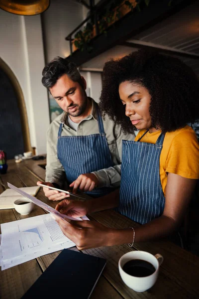 İş arkadaşları borcun özgün kahve dükkanının finansmanını hesaplayan evraklara bakmasından endişe ediyor.
