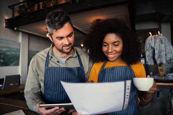 Colleghi che discutono di lavoro in possesso di carta di lavoro e tablet digitale bere caffè caldo nel caffè alla moda — Foto Stock