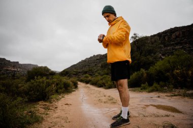 Genç aktif erkek sporcu dağda yürüyüş yaparken akıllı adımlarla kayıyor..