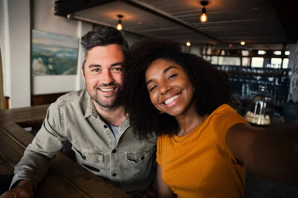 Couple multi race souriant joyeusement dans la caméra dans un café lumineux — Photo