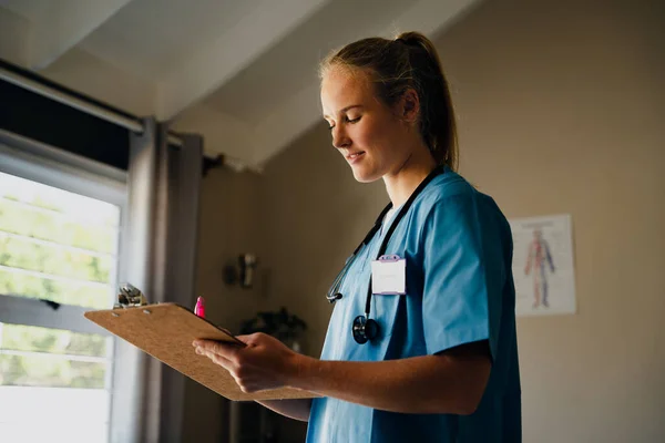 Καυκάσιες γυναίκες νοσηλεύτριες που γράφουν ασκήσεις για ασθενείς που στέκονται στην κλινική — Φωτογραφία Αρχείου