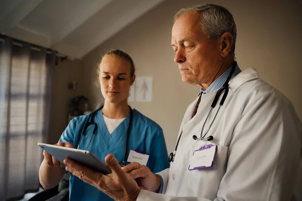 Άντρας γιατρός και γυναίκα νοσοκόμα συζητούν τα αποτελέσματα μαζί σε ένα ψηφιακό δισκίο — Φωτογραφία Αρχείου