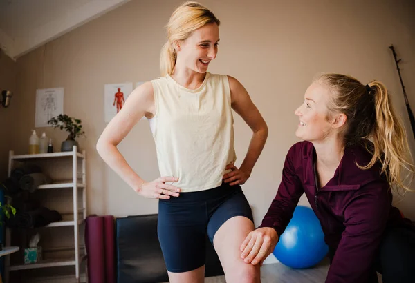 Female patient holding balance while physio-therapist observes core stability standing in exercise studio — Stockfoto