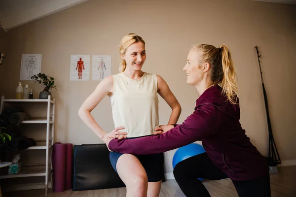 Physiotherapeutin korrigiert Kernstabilität einer Teenie-Patientin, die auf einem Bein im Studio steht — Stockfoto
