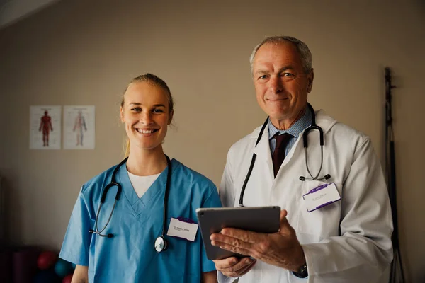 Portrait of Female and Male Doctors in scrubs and lab coat with digital tablet — Photo