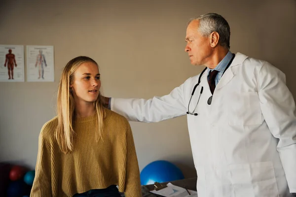 Elderly male doctor assesses neck of young female patient — Photo