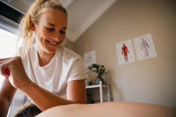 Physio-therapist massaging neck out injured patient lying on bed in rehab studio — Stok fotoğraf