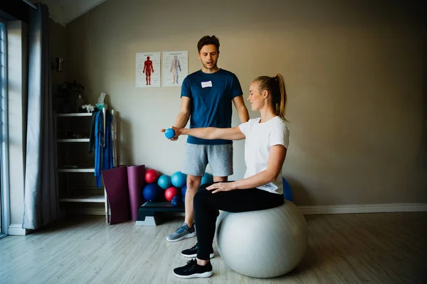 Caucasian male trainer or therapist training young Caucasian female in home gym, recovery and rehabilitation, physiotherapist — Stockfoto