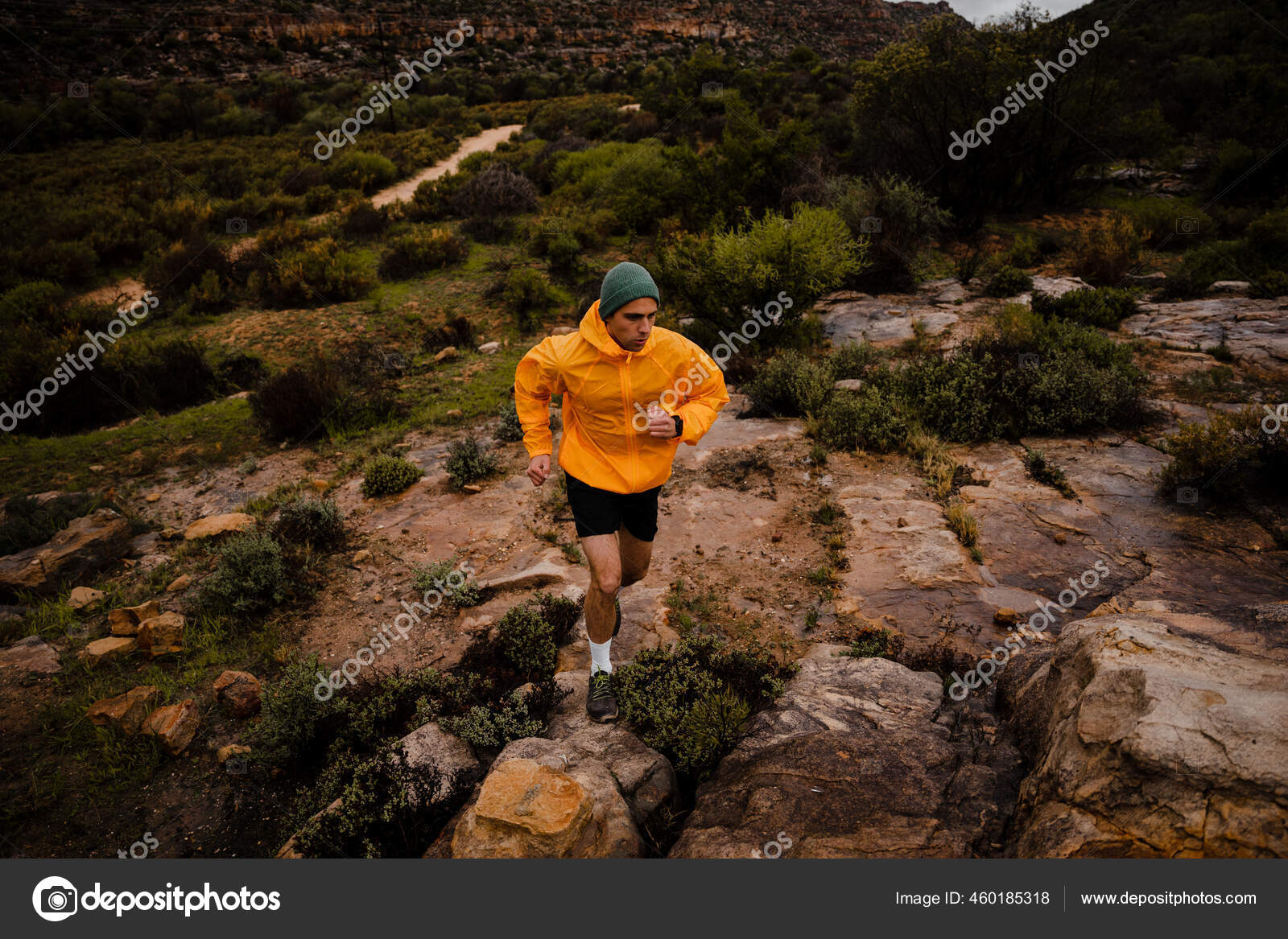 Wide angle fit young male trail runner sprinting up wet rocks on