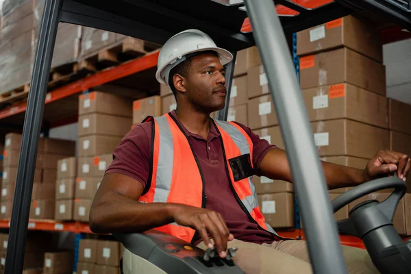 Male factory worker driving forklift indoors locating parcels to ship for delivery 