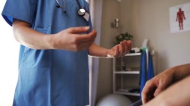 Nurse squeezing hands of patient while standing in clinic.