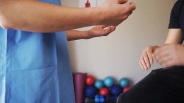 Nurse holding hands with patient sitting on bed in clinic.
