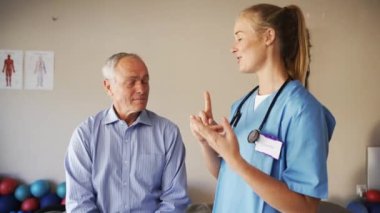 Young Caucasian female doctor in scrubs advising elderly male patient next steps