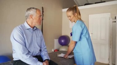 Female intern testing flexibility of knee of elderly patient.