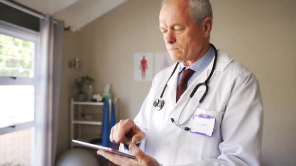 Pacientes de edad avanzada Caucásico médico masculino o especialista en mecanografía y presentación de resultados en tabletas digitales en la clínica — Vídeos de Stock