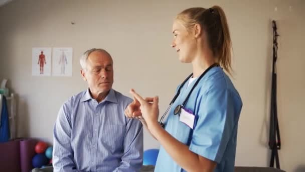 Female doctor discussing steps to recovery with elderly male patient — Stock video