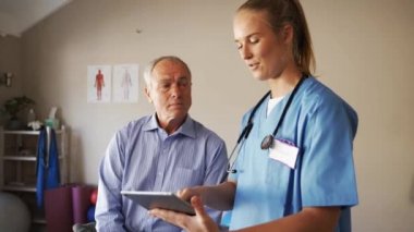 Female doctor in scrubs discussing male patients results on digital tablet
