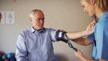 female doctor taking blood pressure of elderly man.