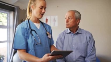female doctor in scrubs giving medical advice via a tablet.