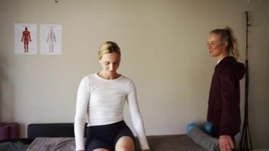 young physiotherapist tests shoulder and elbow flexibility of patient