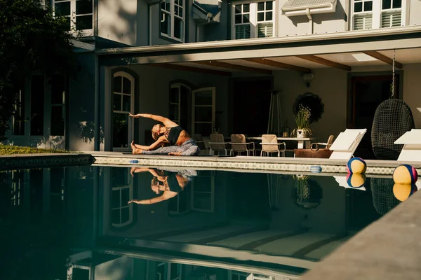 Καυκάσια γυναίκα έφηβος τέντωμα στο σπίτι χαλάρωση δίπλα στην πισίνα — Φωτογραφία Αρχείου