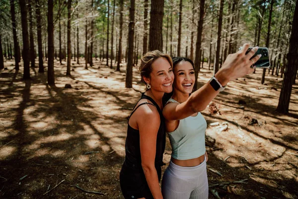 Δύο φίλοι στέκονται στο δάσος βγάζοντας selfie με την κυτταρική συσκευή — Φωτογραφία Αρχείου