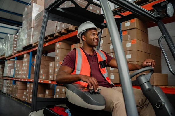 Depoda forklift kullanan etnik işçi teslimat paketlerini yerleştiriyor. 