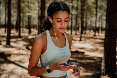 Karışık ırk dişileri ormanda egzersiz yapıyor kulaklıklarla kulaklık dinliyor.