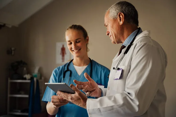 Médecins masculins et féminins souriant en regardant les résultats positifs sur tablette numérique. — Photo