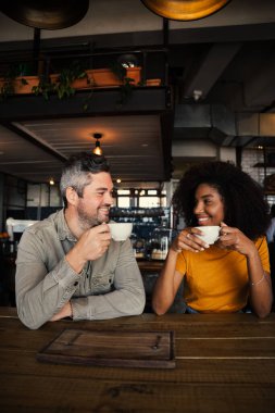 Mutlu romantik çift, modaya uygun bir kafede otururken bir fincan kahve içip sohbet ediyor. 