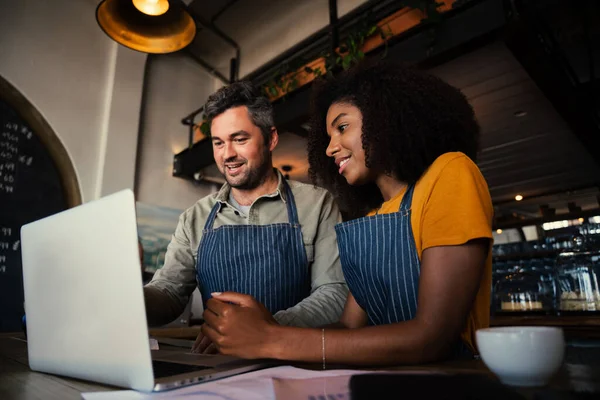 Responsabile della formazione tirocinante caffetteria che mostra il menu sul computer portatile mentre beve caffè caldo nel caffè — Foto Stock