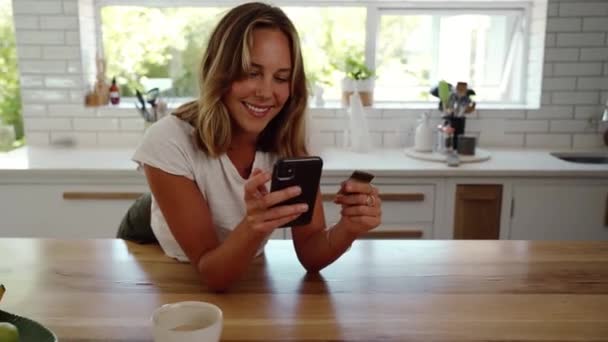 Blank vrouw tiener staande in keuken het maken van online betaling met credit card en mobiele apparaat — Stockvideo