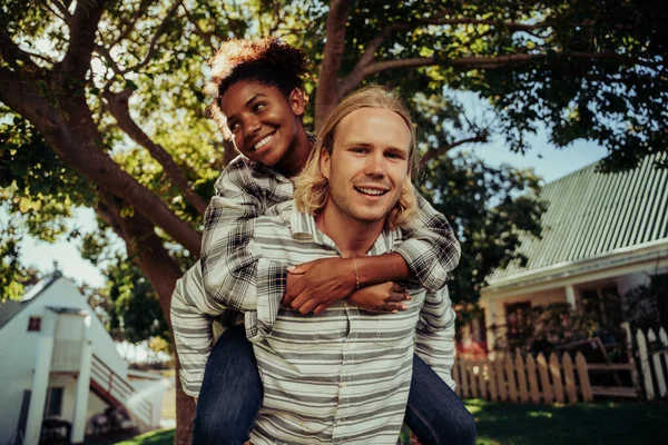Meerdere ras paar bonding samen lachen terwijl de man draagt vrouwelijke op de rug — Stockfoto