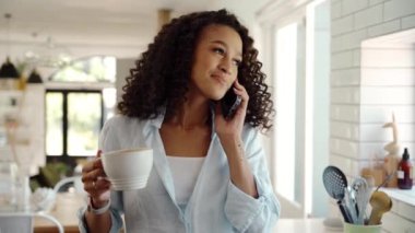 Karışık ırk kadınları evde çalışıyor. Hücresel cihazla sohbet ediyor, sıcak kahve içiyor.