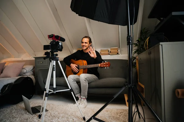 Caucasian male teaching guitar online with video camera and vlog setup, behind the scenes
