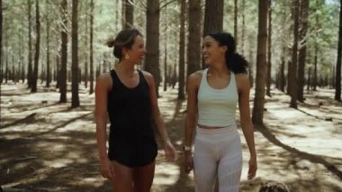 Hücresel cihazda kaydırma yaparken ormanda dolaşan melez kadın arkadaşlar. 