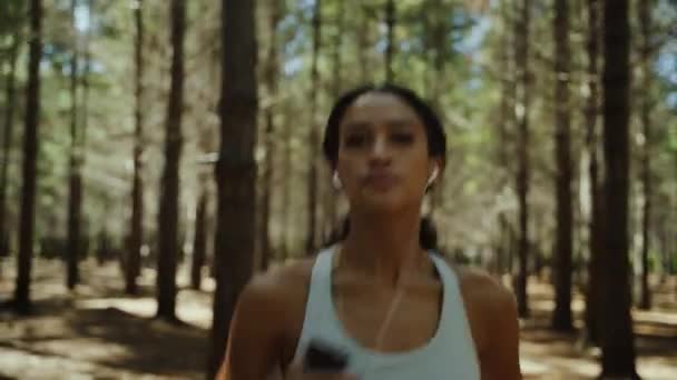 自然の中で自然の中でイヤホンで音楽を聴く運動中の混合レースの女性 — ストック動画