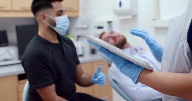 Erkek hemşire hastayla konuşurken beyaz kadın hemşirenin dijital tabletle yazışmasını kapat. 