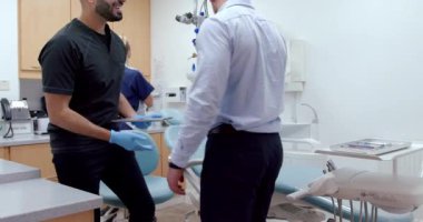 Beyaz erkek hasta doktor muayenehanesine geliyor. Yatakta oturmuş hemşirelerle sohbet ediyor.