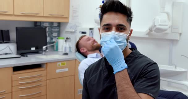 Enfermeira vestindo de pé na sala do dentista tirando a máscara cirúrgica para sorrir para a câmera — Vídeo de Stock