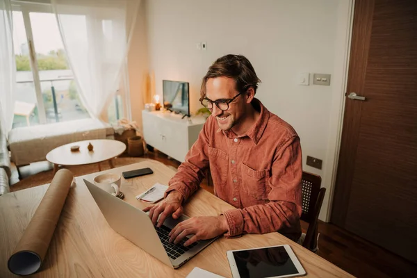 Caucasian male student typing on laptop working at home desk set up — Zdjęcie stockowe