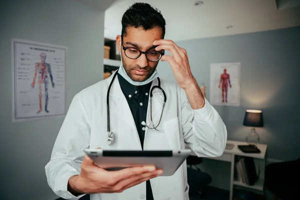 Gemengde race mannelijke verpleegkundige angstig voor drukke dag vooruit te houden digitale tablet — Stockfoto