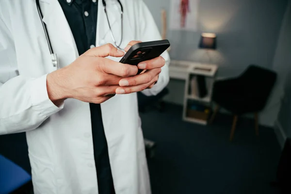 Médecin masculin debout dans la clinique tapant sur l'appareil cellulaire — Photo