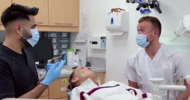 Caucásico paciente femenino acostado en la cama de los médicos con el marido médico masculino limpia los dientes — Vídeos de Stock