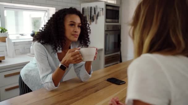 Blandade ras kvinnliga vänner chattar i köket dricka kaffe — Stockvideo