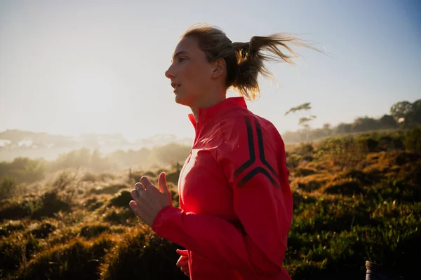 Atleta feminina em ação correndo ao ar livre no caminho na floresta terrestre. — Fotografia de Stock