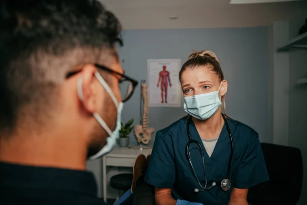 Μικτή φυλή αρσενικό ασθενή στέκεται με γυναίκα νοσοκόμα στο γραφείο γιατρούς — Φωτογραφία Αρχείου