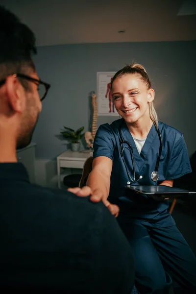 Blanke vrouwelijke verpleegster staan in kliniek chatten met mannelijke patiënt — Stockfoto